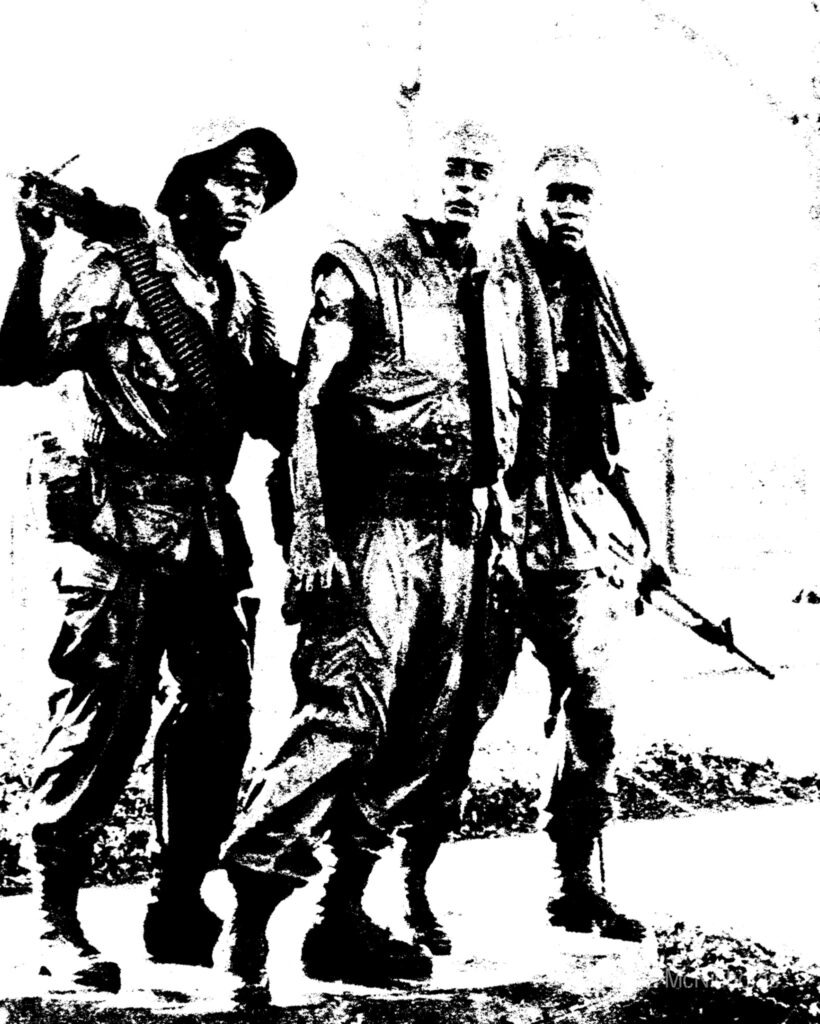 Three soldiers in military fatigues, armed and focused, march forward in a stark black-and-white setting, exemplifying a combat scenario.
