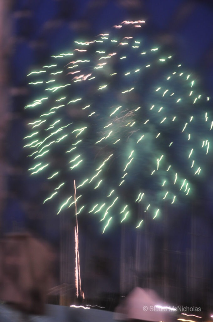 Colorful fireworks burst in the night sky, creating a vibrant display above silhouetted masts, capturing a festive atmosphere.