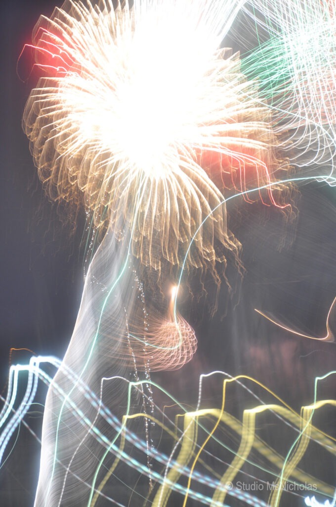 Colorful, abstract fireworks explode against a dark sky, with swirling light trails creating a dynamic visual effect. Suitable for celebratory contexts.