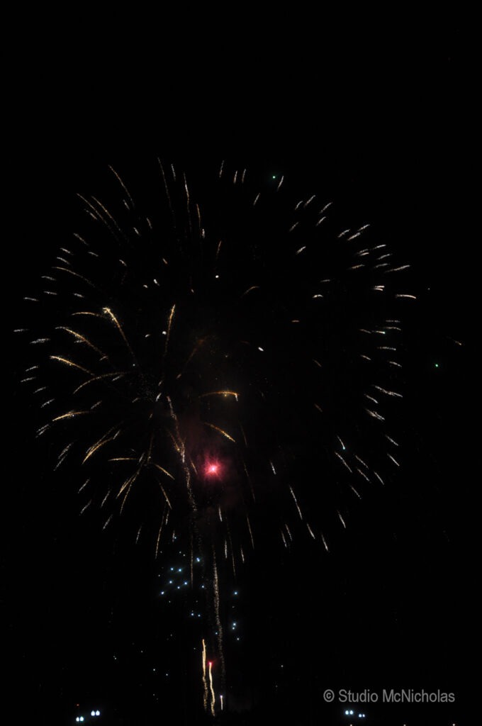Colorful fireworks burst against a dark night sky, creating a festive atmosphere, likely captured during a celebration or holiday event.