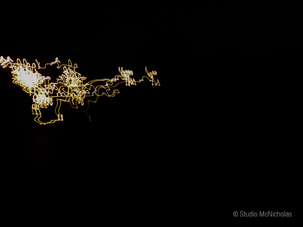 Abstract light patterns against a dark background create a dynamic visual effect. This image explores movement and energy through light.